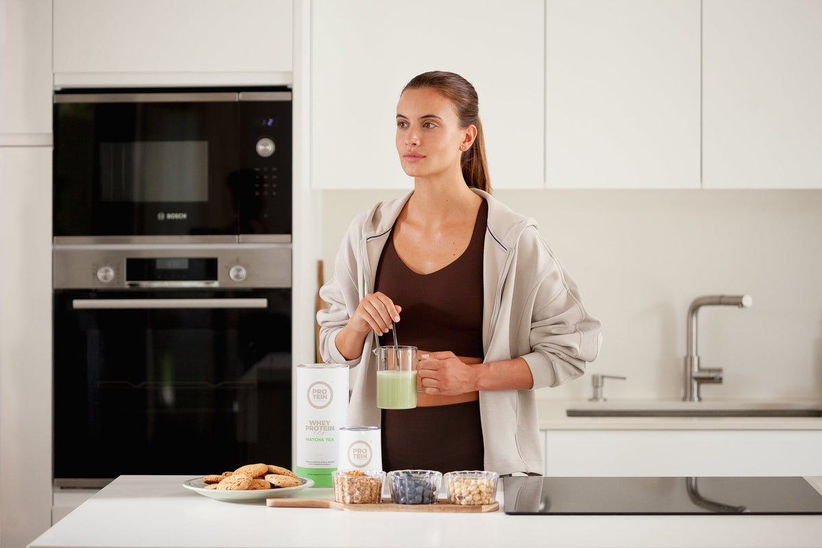 Mujer con ropa deportiva preparando un batido en la cocina